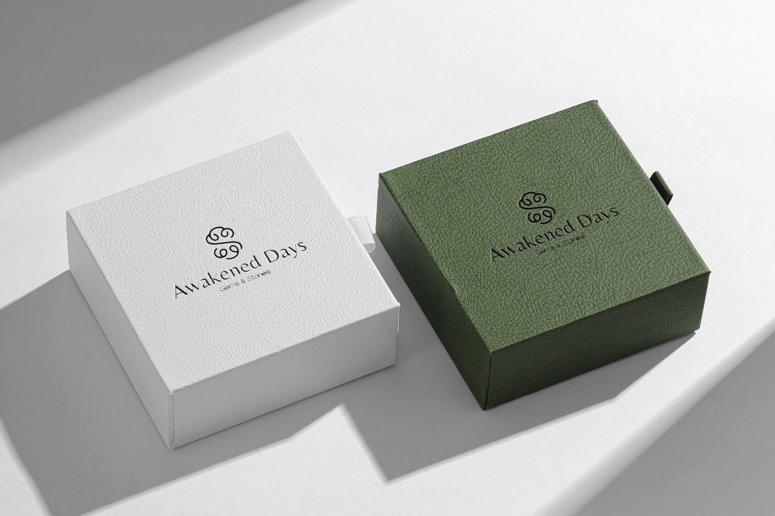 Two boxes, one white and one green, with 'Awakened Days' branding on a light gray background.