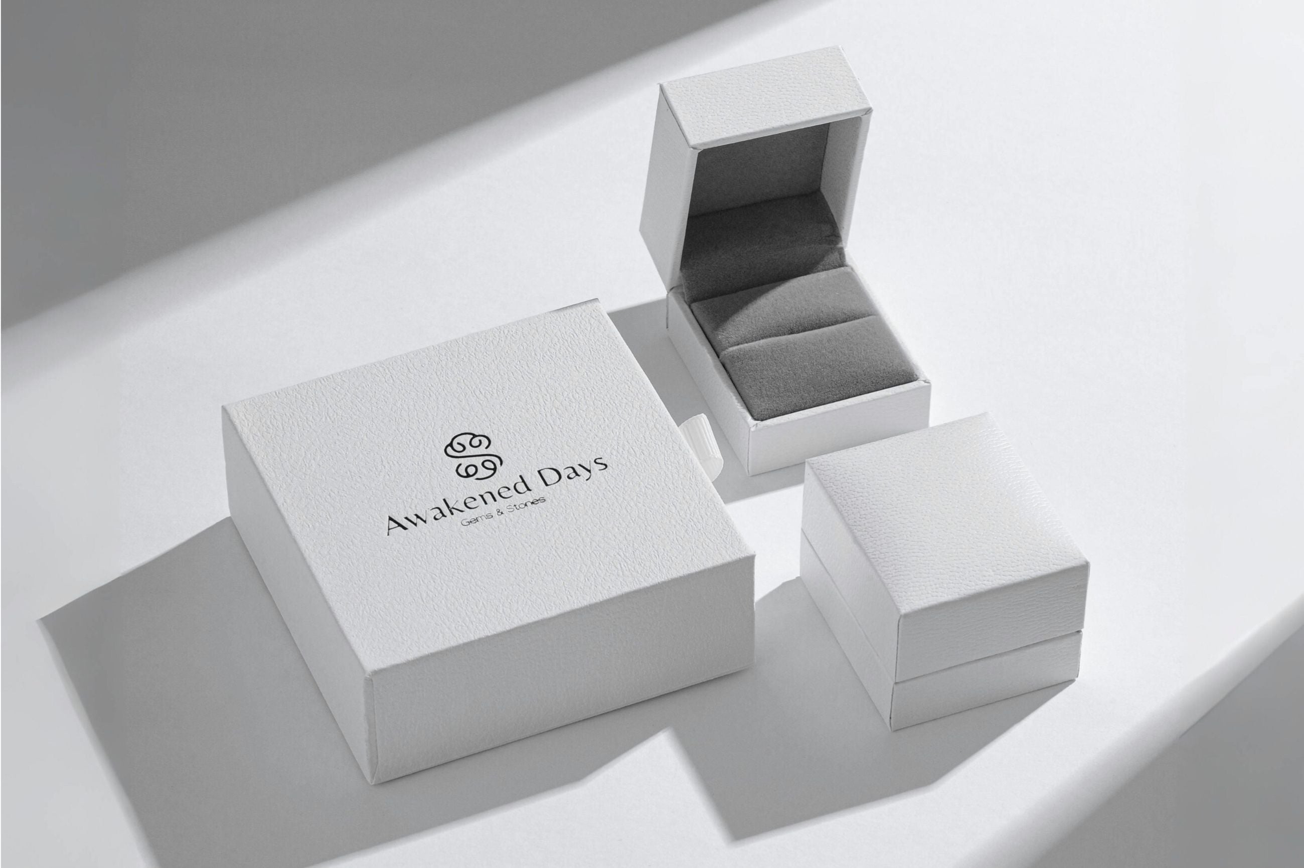 Jewelry box with 'Awakened Days' branding on a light gray background